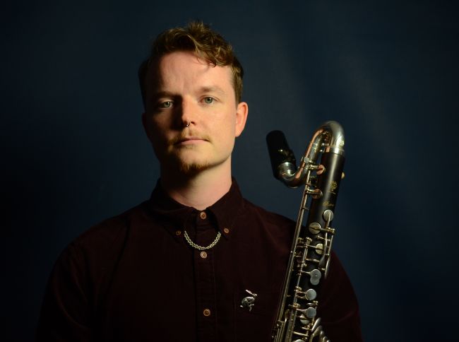 Colour photo of Christopher Moriarty holding a bass clarinet