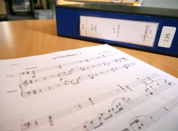 The opening page of a music score against the backdrop of an archival storage box