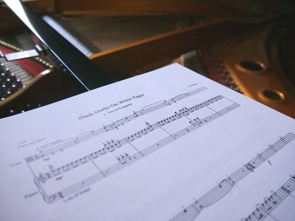 Music score lying against the backdrop of an open grand piano