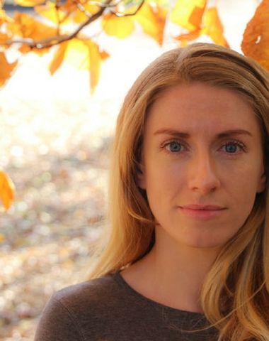 Composer Emma O'Halloran stands in front of a background of autumn leaves